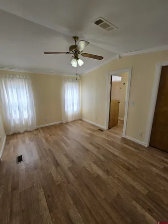 a view of an empty room with window and wooden floor