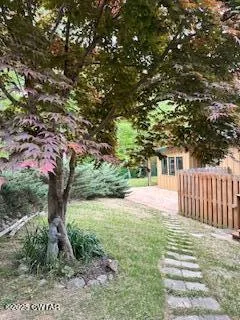 a view of a backyard with large trees and wooden fence