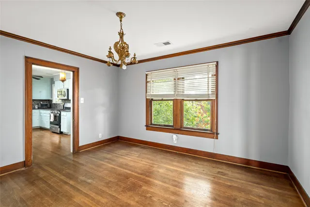 an empty room with chandelier fan and windows