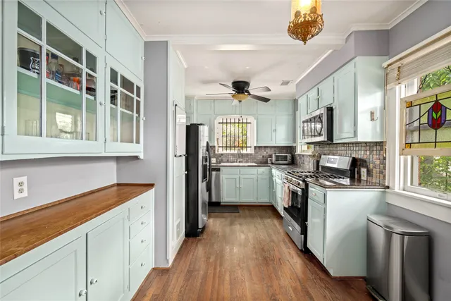 a kitchen with cabinets wooden floor and stainless steel appliances