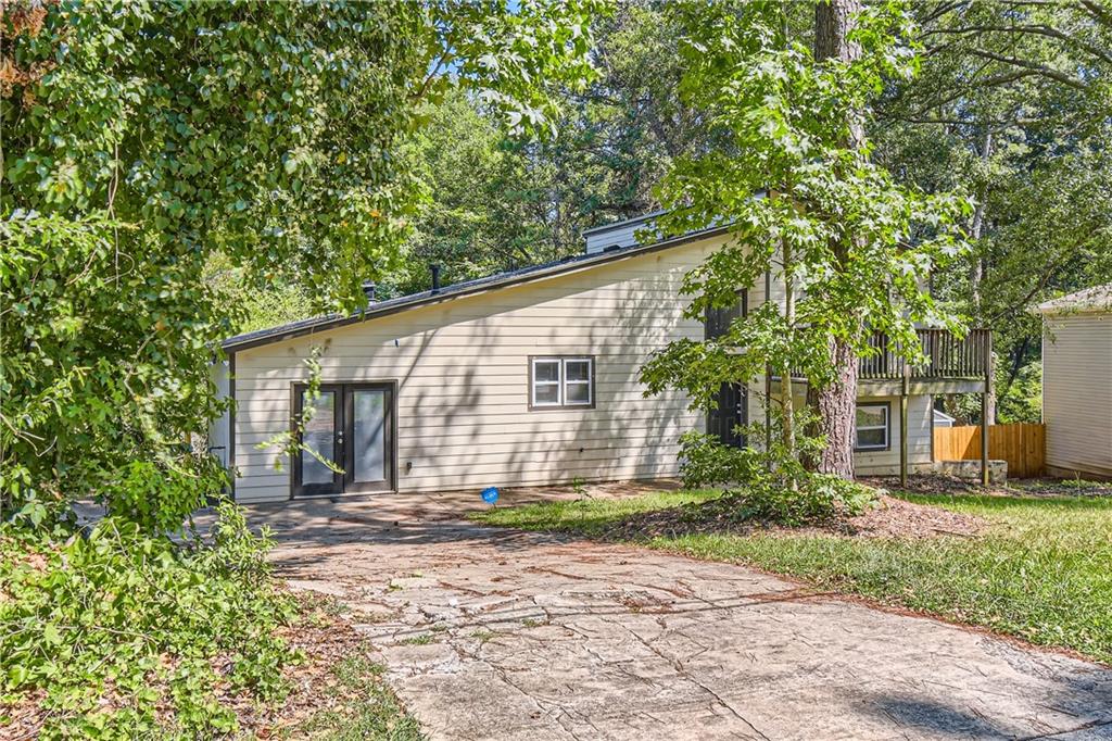 a backyard of a house with large trees and plants