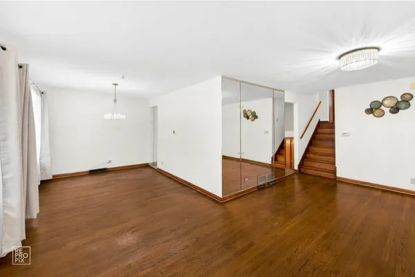 a view of an empty room with wooden floor and stairs