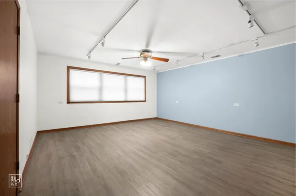 an empty room with wooden floor chandelier fan and windows