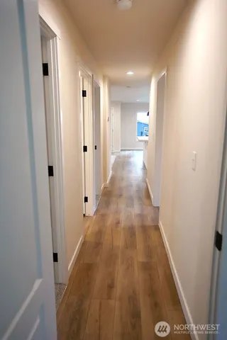 a view of a hallway with wooden floor and a bathroom