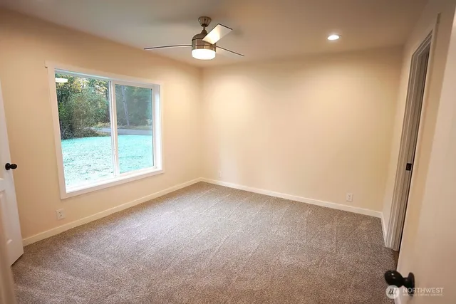 an empty room with wooden floor a ceiling fan and windows