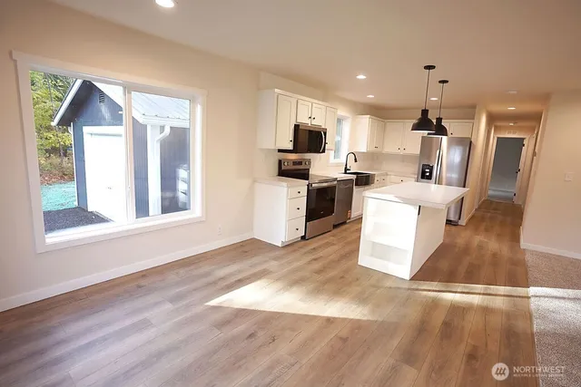 a view of a kitchen with a sink wooden floor and a living room