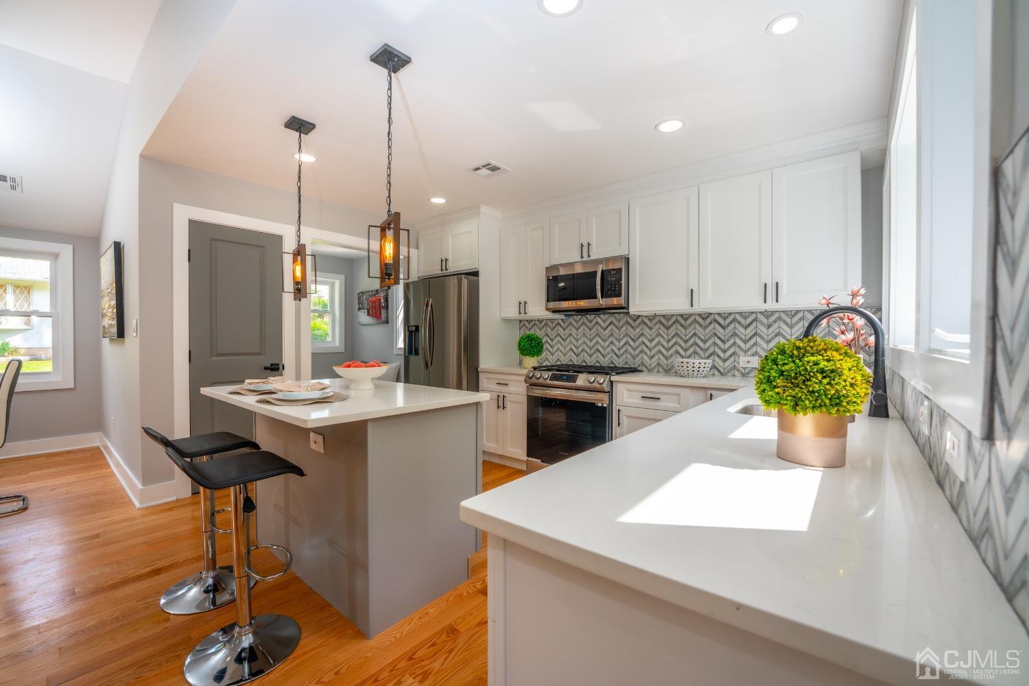 45 East Cliff Road Colonia, NJ 07067 - Photo 10 of 31 a kitchen with stainless steel appliances kitchen island granite countertop a sink a stove and a wooden floors