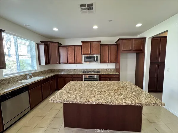 a kitchen with kitchen island granite countertop wooden cabinets a refrigerator and a sink