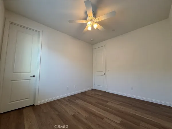 a view of a room with wooden floor and a ceiling fan
