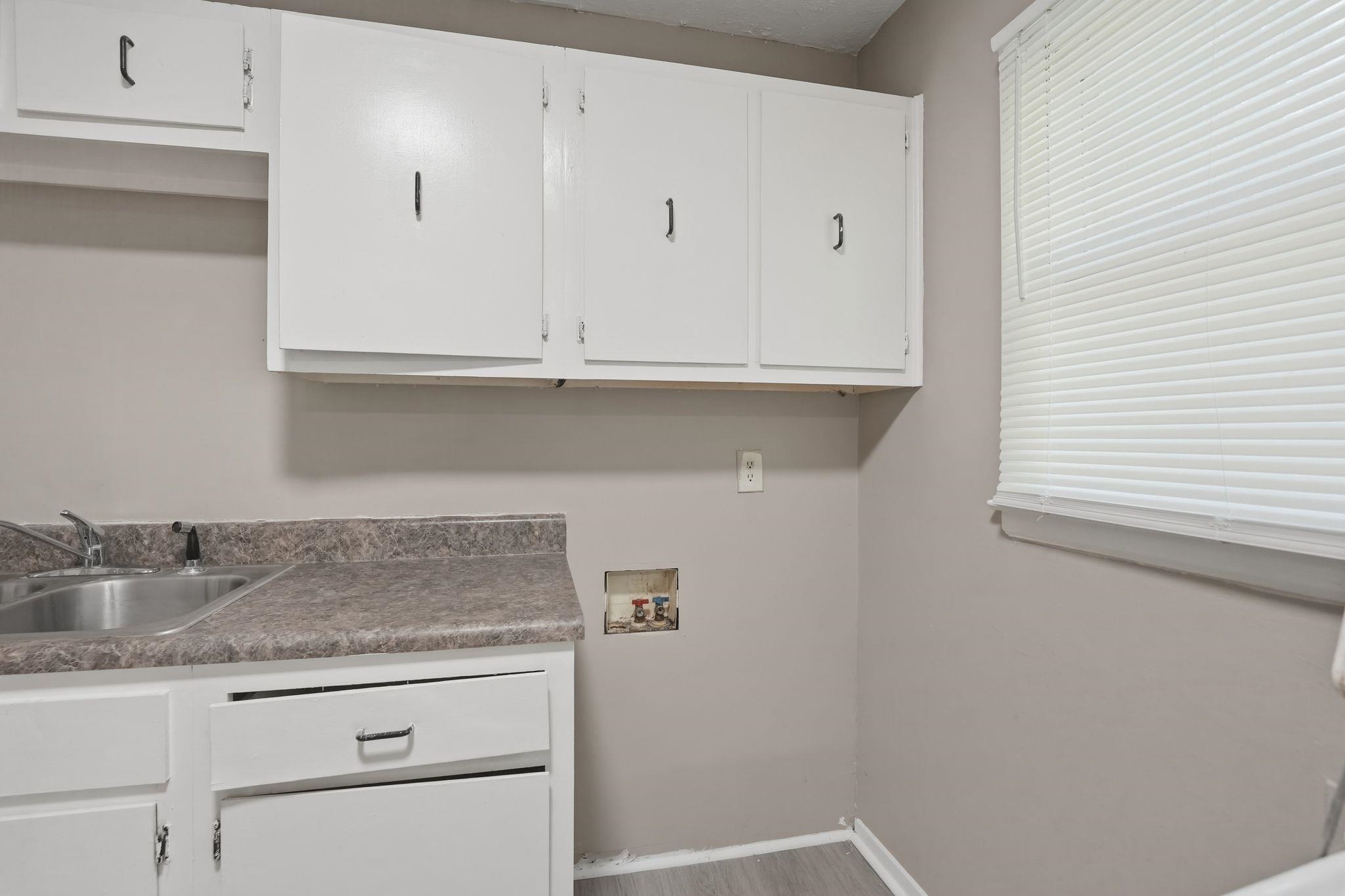 4955 Stacey Road Memphis, TN 38109 - Photo 34 of 35 Utility area featuring white cabinetry, a stainless steel sink with a single-handle faucet, a laminate countertop, and neutral-toned walls