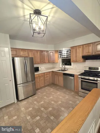 a kitchen with stainless steel appliances granite countertop a sink a stove a refrigerator cabinets and a dining table