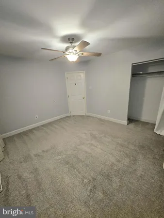 an empty room with a chandelier fan and windows