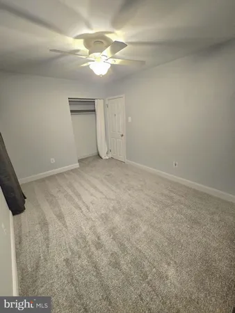 an empty room with a chandelier fan and windows