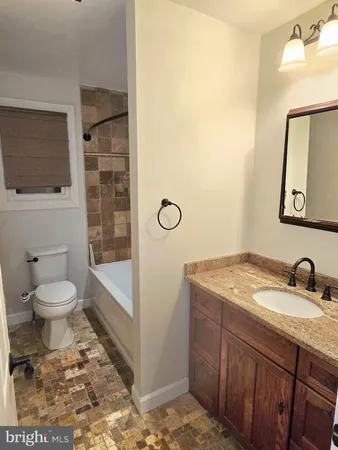 a bathroom with a granite countertop sink a mirror and a toilet