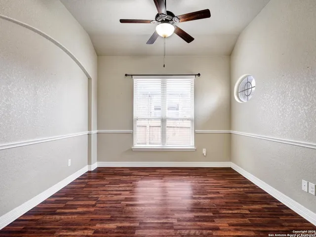 a view of empty room with wooden floor and fan