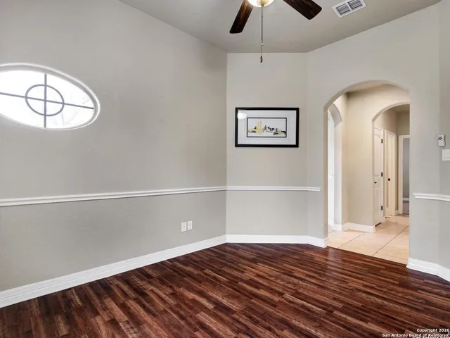 a view of empty room with wooden floor and fan