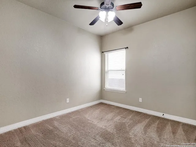 an empty room with a window and a fan