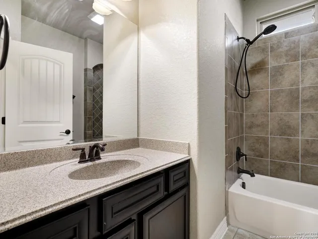a bathroom with a granite countertop sink a mirror and a bathtub