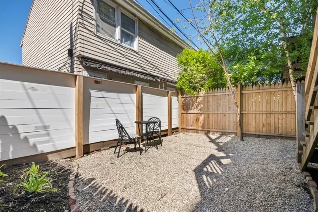 a backyard of a house with chairs and wooden fence