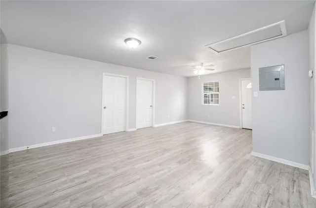 an empty room with wooden floor and windows