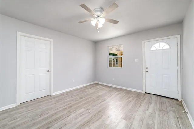 an empty room with wooden floor and a ceiling fan