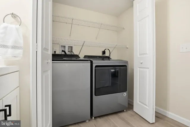 a utility room with stainless steel appliances wooden floor washer and dryer
