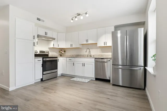 a kitchen with white cabinets stainless steel appliances and a refrigerator