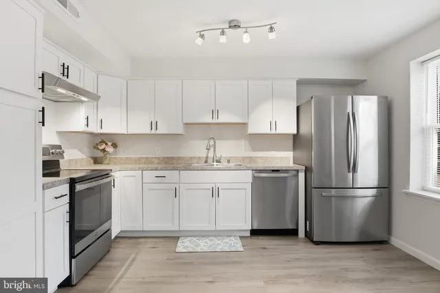 a kitchen with granite countertop a refrigerator stove top oven and cabinets