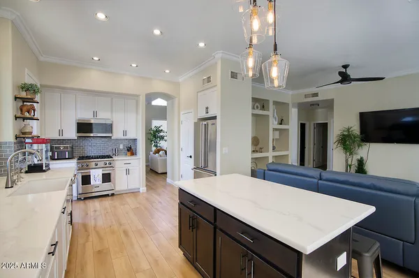 a kitchen with stainless steel appliances a stove top oven a sink dishwasher and a refrigerator with wooden floor