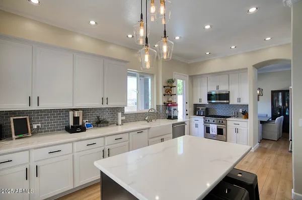 a large kitchen with stainless steel appliances kitchen island granite countertop a refrigerator and a sink