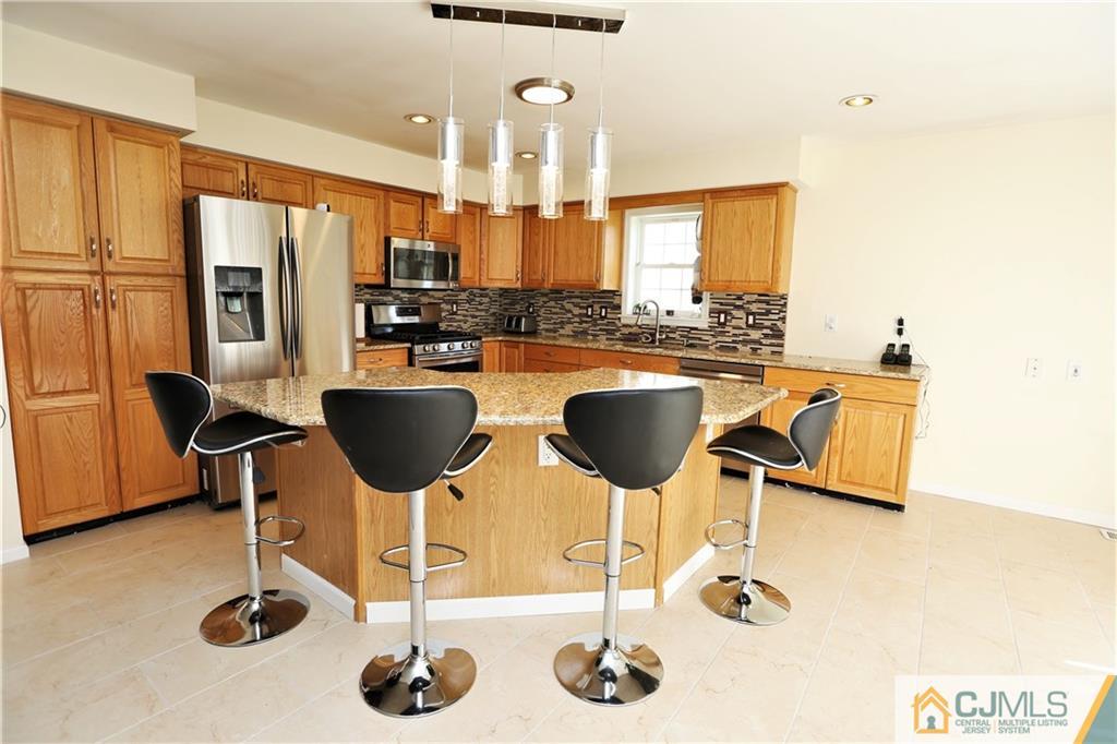 543 Georges Road Dayton, NJ 08810 - Photo 11 of 23 a kitchen with stainless steel appliances kitchen island granite countertop a table and chairs