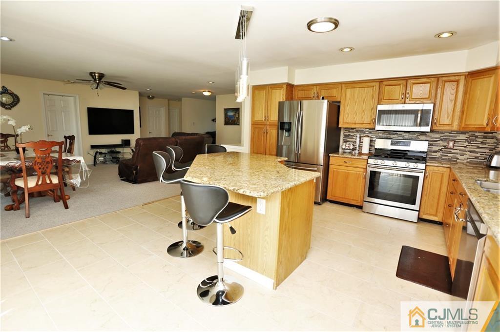 543 Georges Road Dayton, NJ 08810 - Photo 10 of 23 a kitchen with stainless steel appliances kitchen island granite countertop a sink and a refrigerator