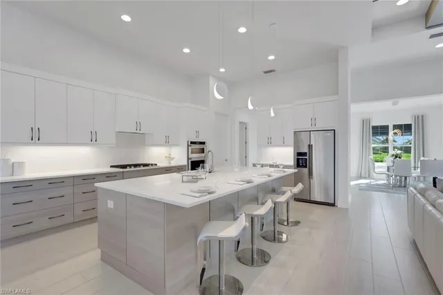 a large white kitchen with stainless steel appliances lots of white furniture