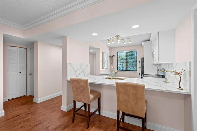 a dining hall with stainless steel appliances granite countertop a stove a sink a dining table and chairs with wooden floor