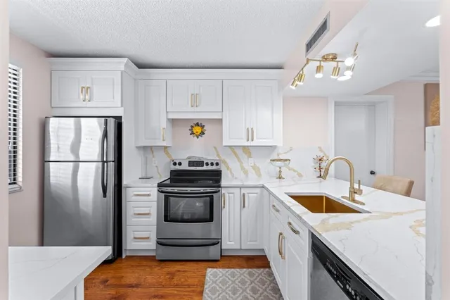 a kitchen with stainless steel appliances granite countertop a sink stove and refrigerator