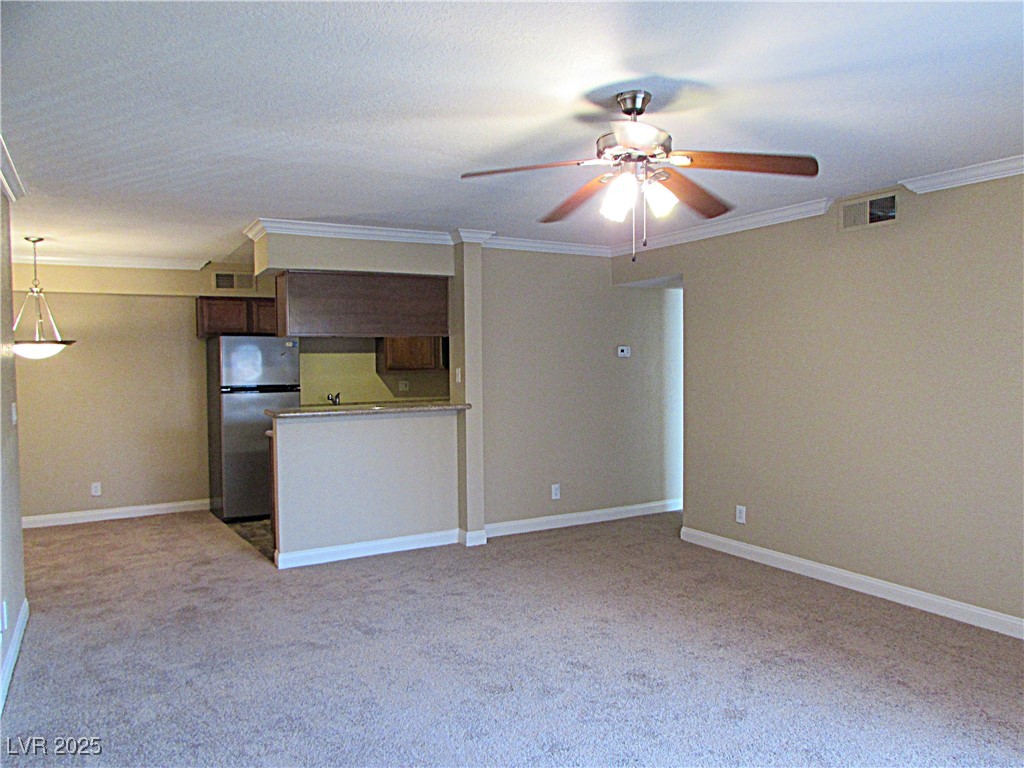 3135 South Mojave Road, Unit 260 Las Vegas, NV 89121 - Photo 4 of 23 Unfurnished living room featuring ornamental molding, light colored carpet, and ceiling fan