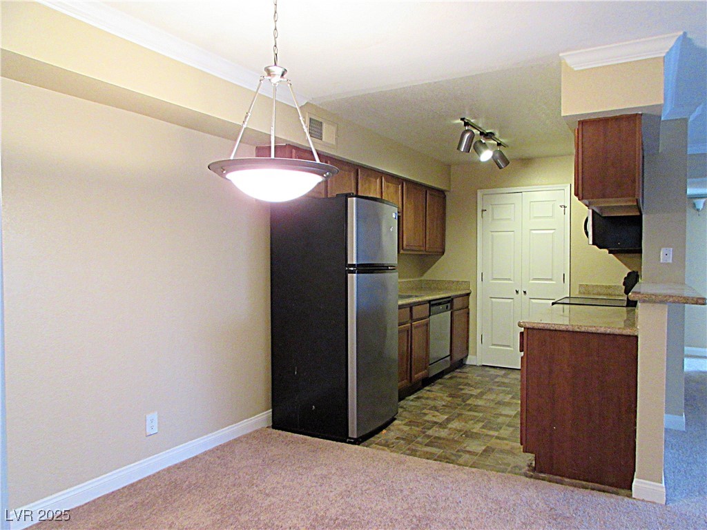 3135 South Mojave Road, Unit 260 Las Vegas, NV 89121 - Photo 5 of 23 Kitchen featuring appliances with stainless steel finishes, brown cabinetry, dark colored carpet, and hanging light fixtures