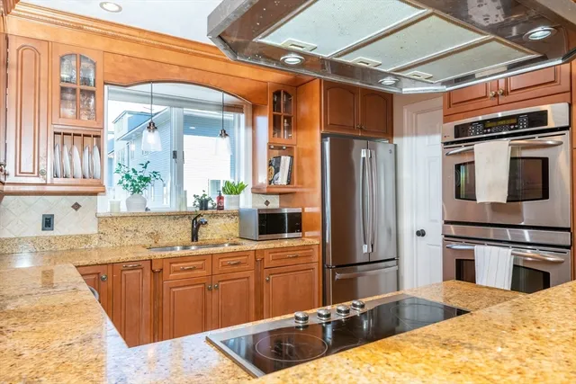 a kitchen with stainless steel appliances kitchen island granite countertop a refrigerator and a stove top oven