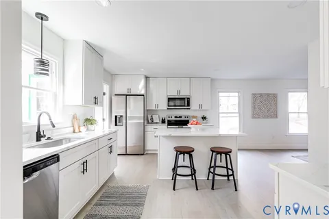 a kitchen with stainless steel appliances a white table chairs refrigerator and sink