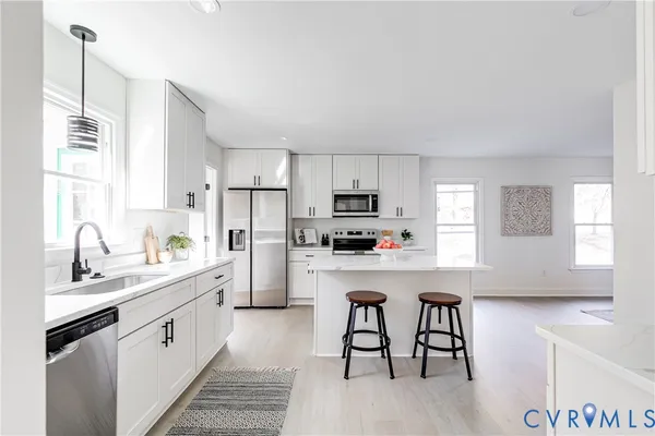 a kitchen with stainless steel appliances a white table chairs refrigerator and sink