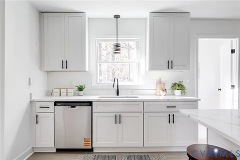 a kitchen with white cabinets and sink