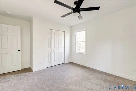 an empty room with a ceiling fan and window