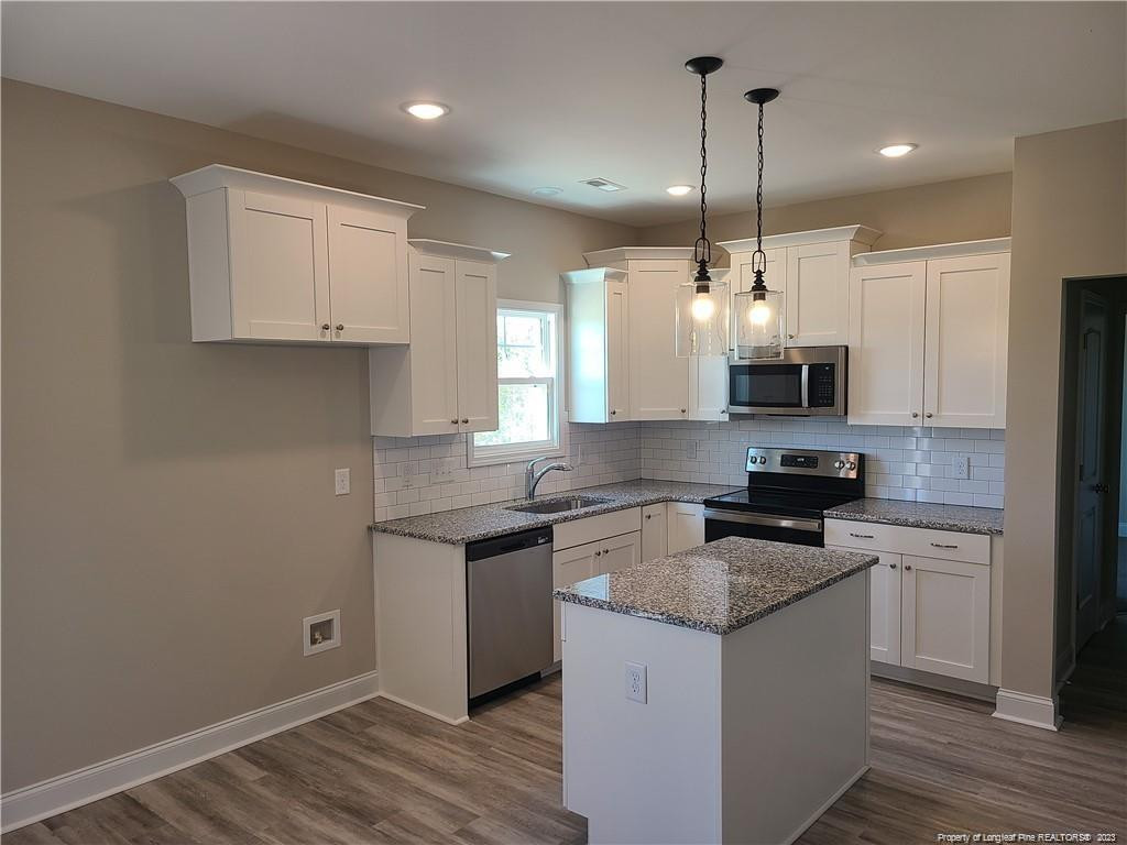 754 Walker (lot 1) Road Rockingham, NC 28379 - Photo 16 of 50 a kitchen with stainless steel appliances granite countertop a sink stove and white cabinets with wooden floor