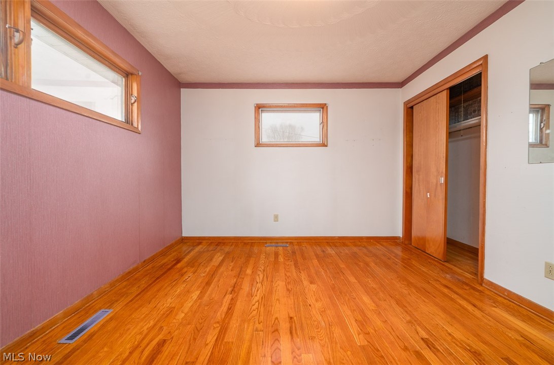 3336 Broad Run Dairy Road Northwest Dover, OH 44622 - Photo 17 of 26 Unfurnished bedroom with light wood-type flooring, multiple windows, a closet, and a textured ceiling
