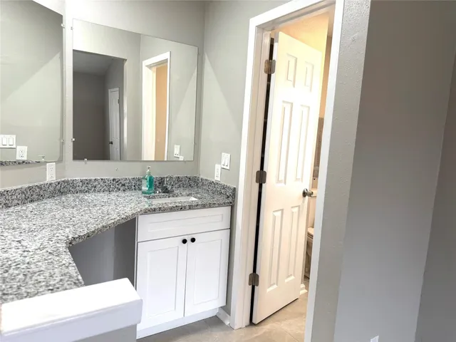 a bathroom with a granite countertop sink and a mirror