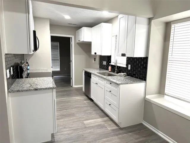 a kitchen with granite countertop white cabinets and white appliances