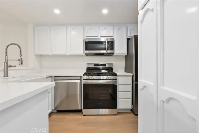 a kitchen with stainless steel appliances granite countertop a stove a sink and a microwave