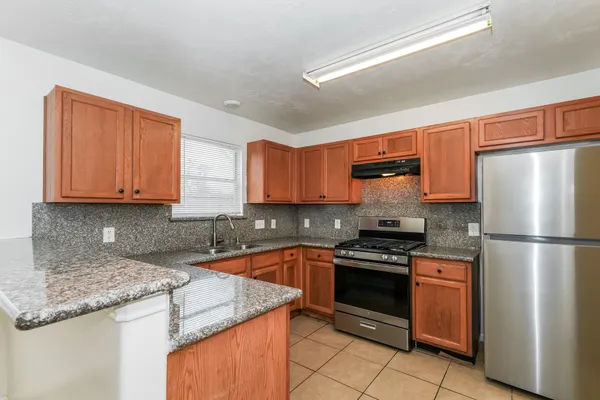 a kitchen with granite countertop a refrigerator sink and cabinets
