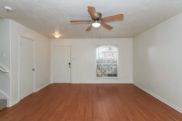 a view of an empty room with wooden floor and a window