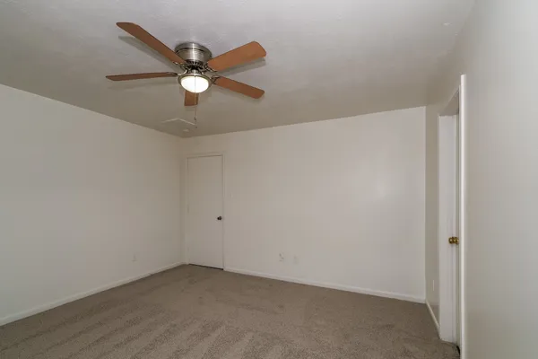 an empty room with closet and ceiling fan